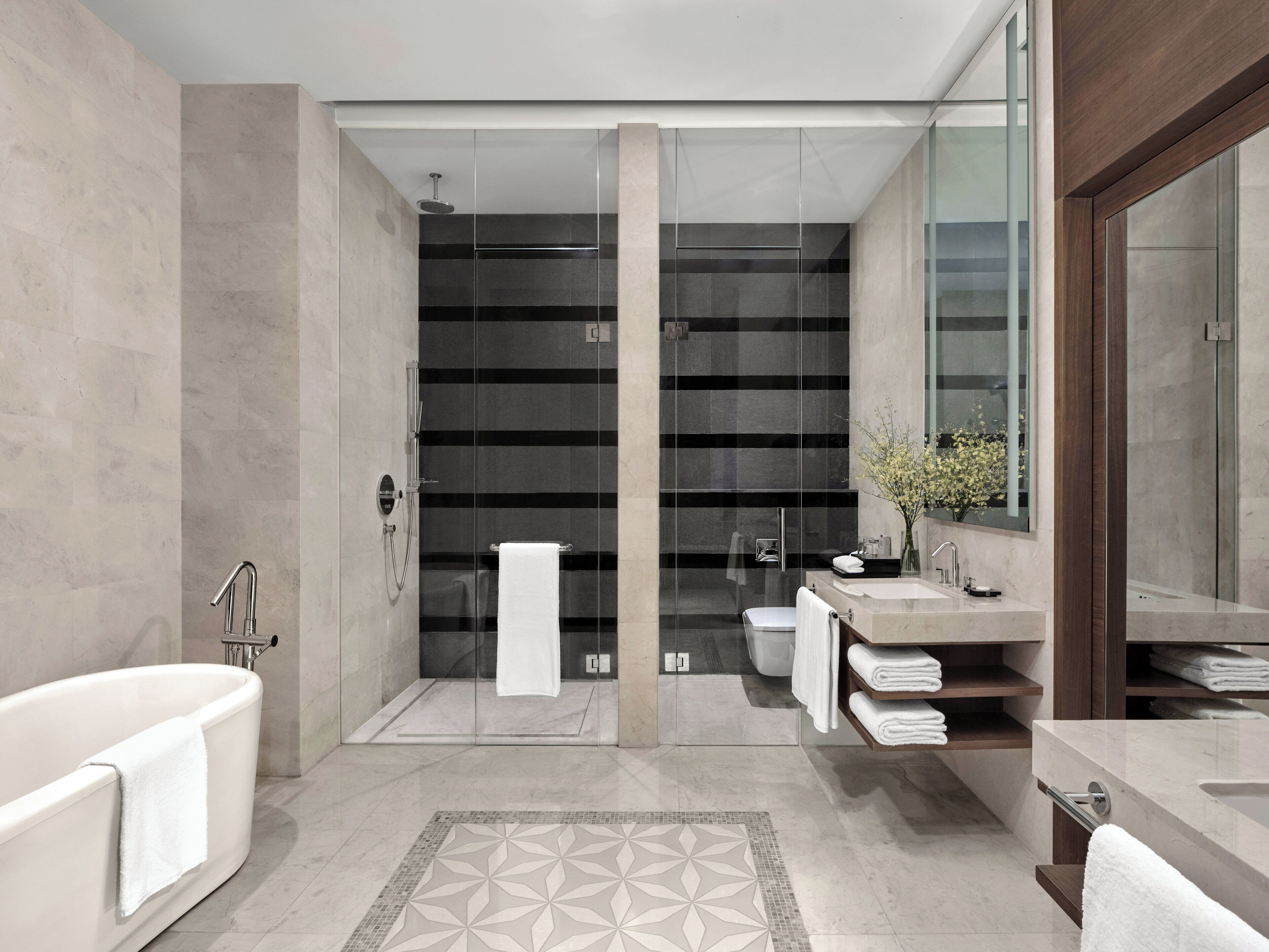 A modern bathroom with a freestanding bathtub, a glass-enclosed shower, and a vanity with a mirror.