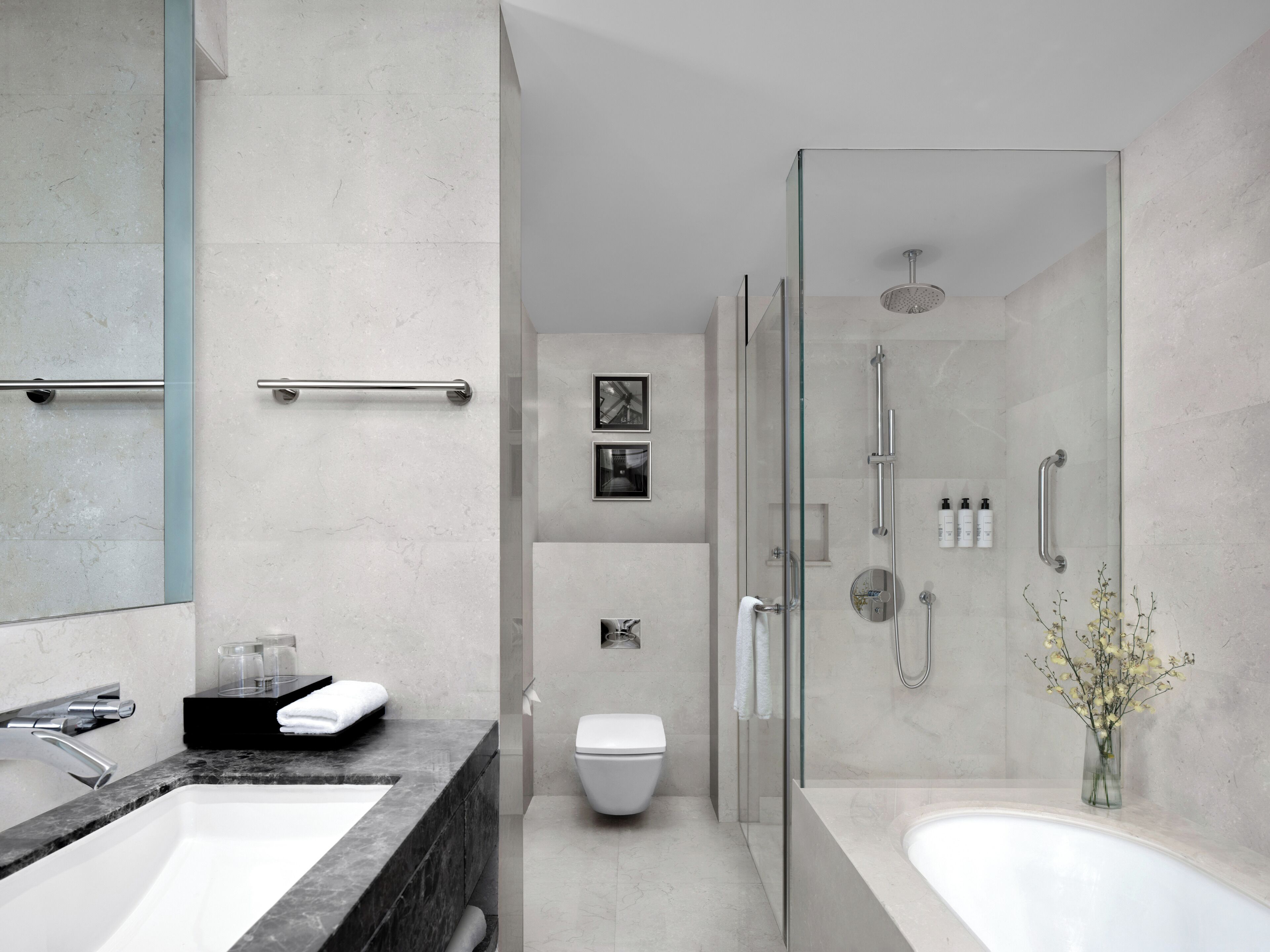 Un baño moderno con ducha de vidrio, inodoro blanco y una bañera grande.