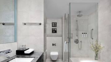 A modern bathroom with a glass-enclosed shower, a white toilet, and a large bathtub.