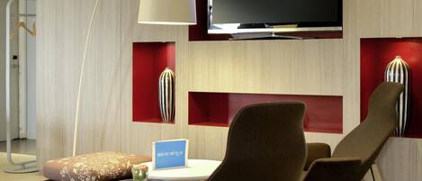 A modern living room with a flat-screen TV, a sofa, a coffee table, and a lamp.