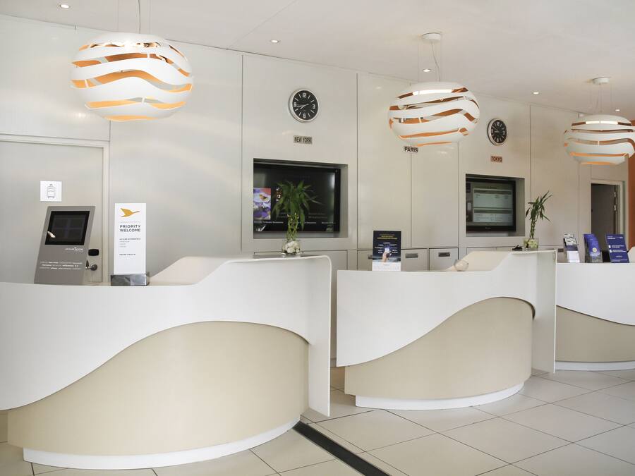 A reception area with three counters, a clock, and a TV screen.