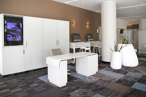 A reception area with a reception desk, two computer monitors, a large flat-screen TV, and a white cabinet.