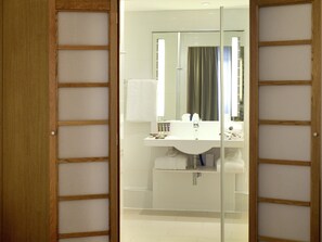 A modern bathroom with a glass partition, a sink, a mirror, and a towel rack.