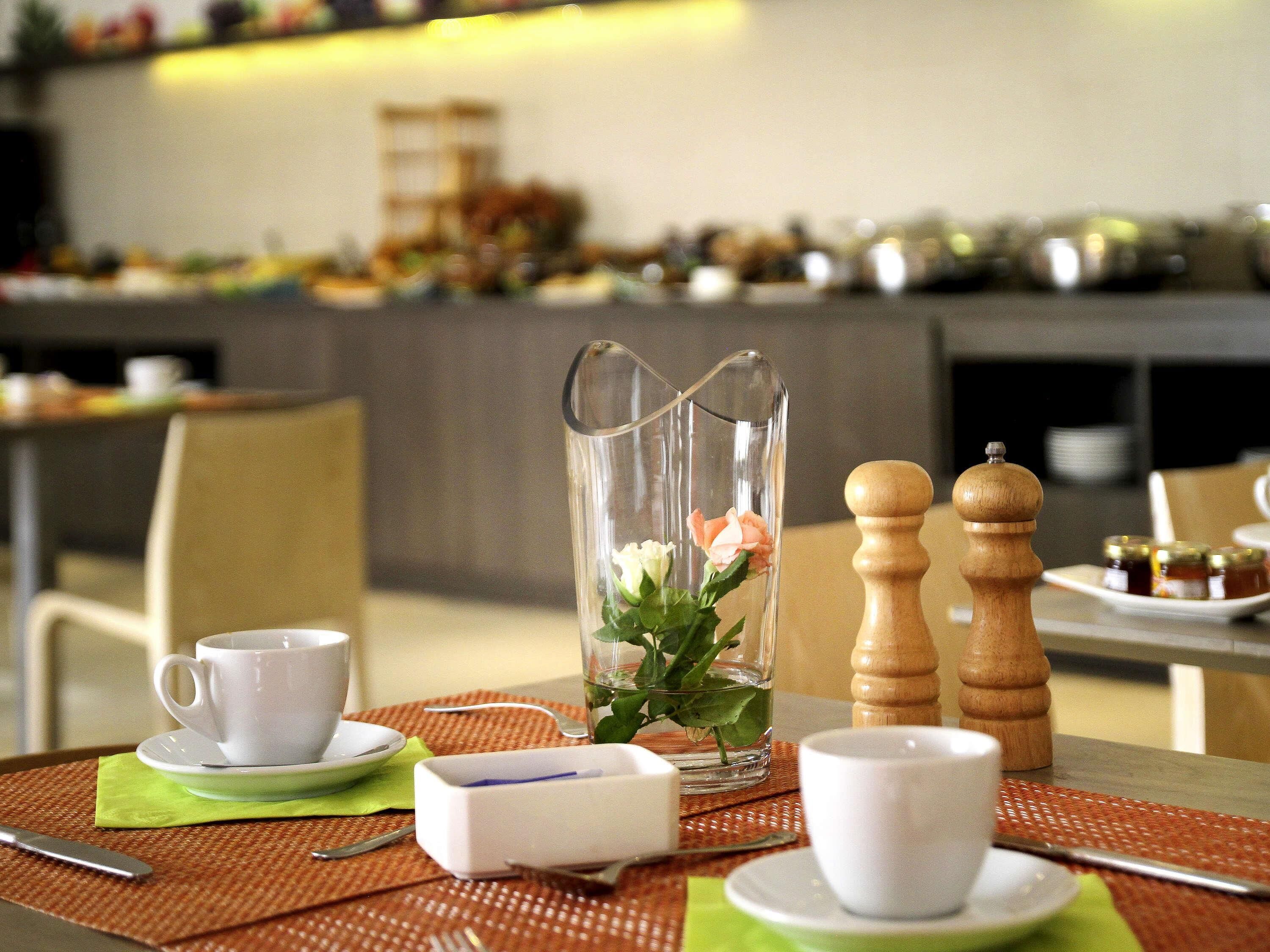A dining table with a pitcher, salt and pepper shakers, a cup, and a plate with a napkin.