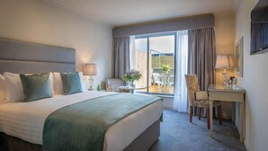A hotel room with a large bed, a desk, a chair, and a view of the outside. - Hyde Hotel (Galway)