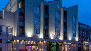 A modern hotel with multiple floors, large windows, and a well-lit entrance.