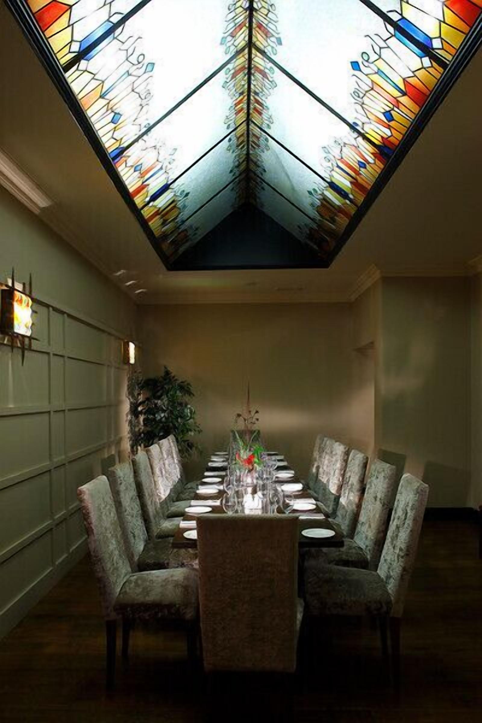 A dining area with a long table set for six, surrounded by upholstered chairs.