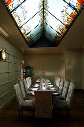A dining area with a long table set for six, surrounded by upholstered chairs. - Hyde Hotel (Galway)