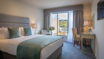 A hotel room with a bed, a desk, a chair, a small table, and a view of the outside.
