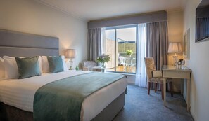 A hotel room with a bed, a desk, a chair, a small table, and a view of the outside. - Hyde Hotel (Galway)