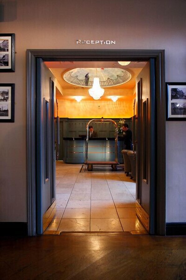 A reception area with a sign above the door, a counter, and a person standing by the counter. - Hyde Hotel (Galway)