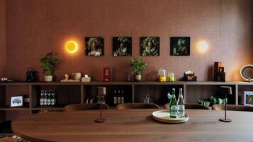 Un comedor con una mesa de madera, sillas y una estantería con diversos objetos, incluyendo botellas y un libro.