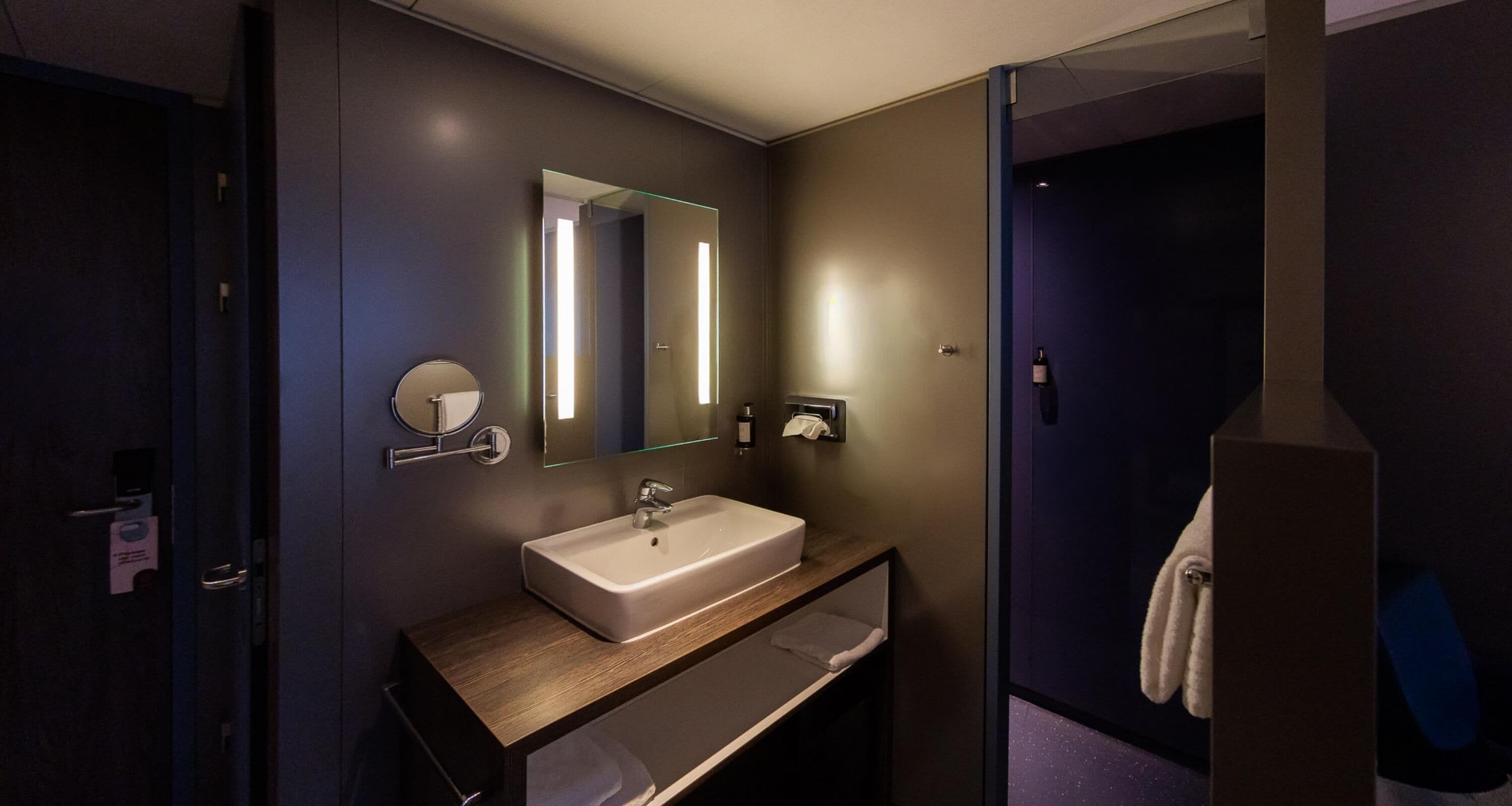 Un baño moderno con un espejo grande, un lavabo y un perchero para toallas.
