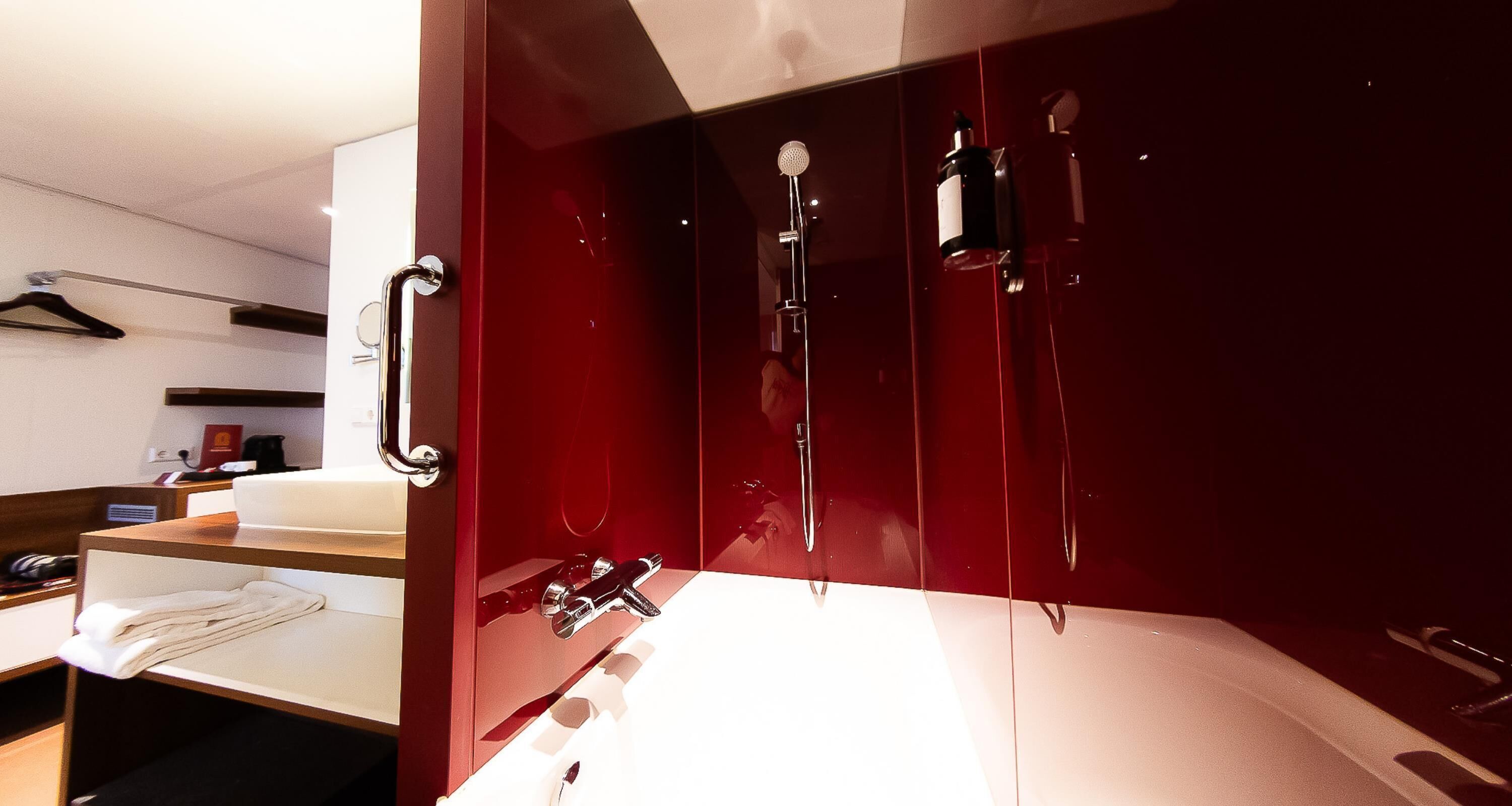 Een moderne badkamer met een rode wastafel, een wastafel en een douchecabine.