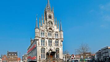 A historic building with a tall spire, large windows, and a central entrance with steps.