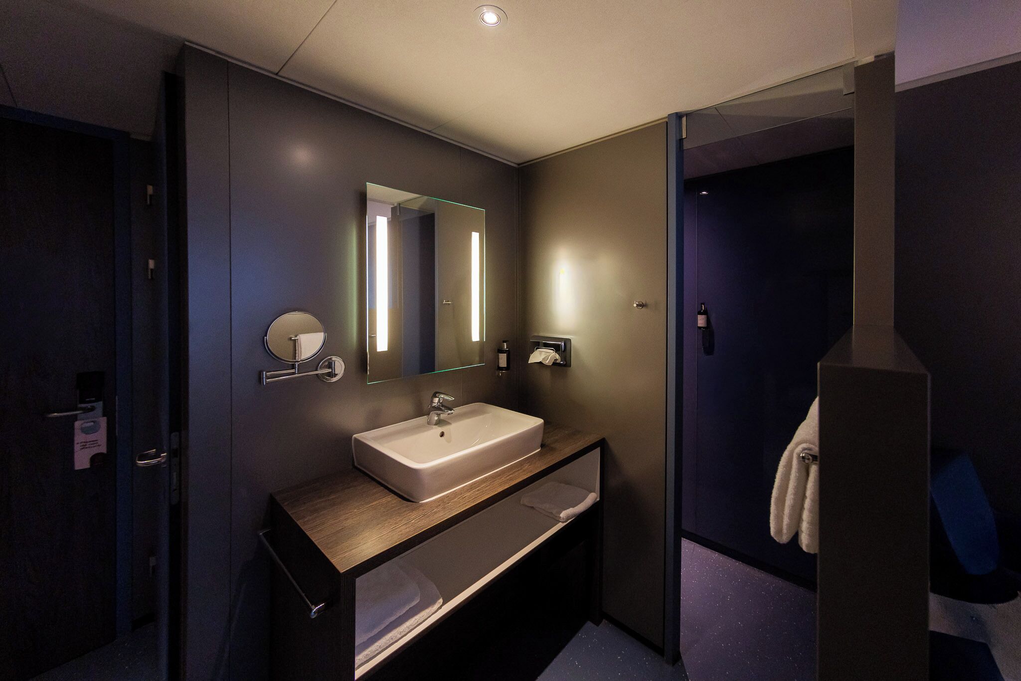 Un baño moderno con un espejo grande, un lavabo y un perchero para toallas.