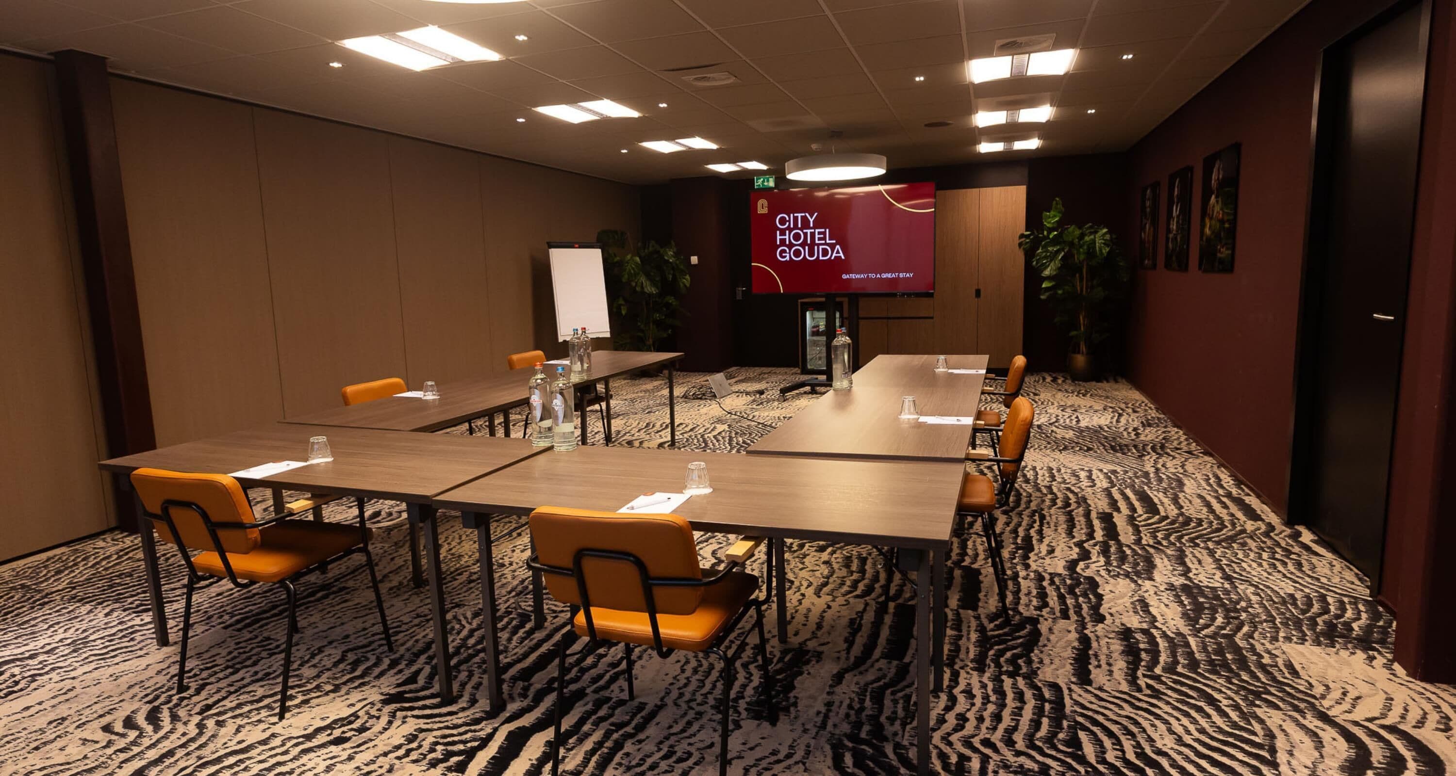 A conference room with a large screen, multiple tables, and chairs.