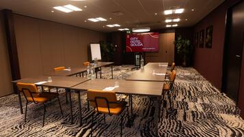 A conference room with a large screen, multiple tables, and chairs.