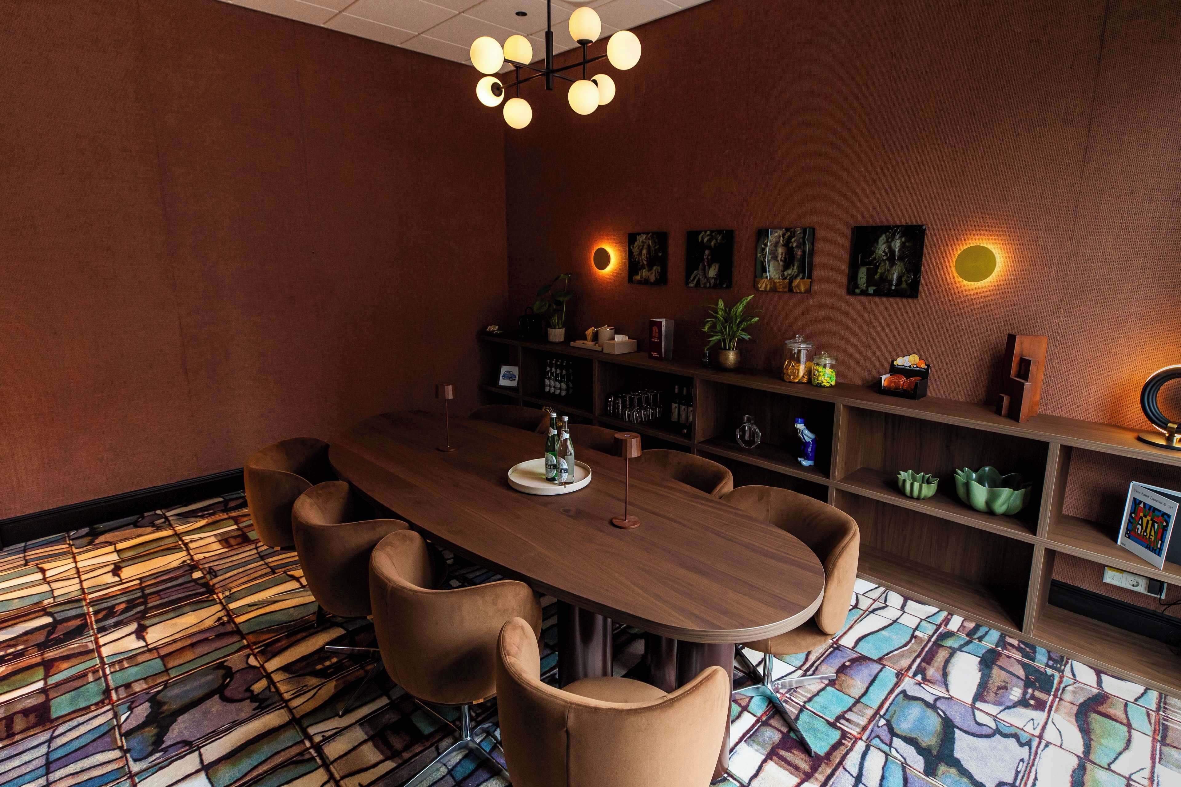 A conference room with a wooden table, six chairs, a chandelier, and a patterned floor.