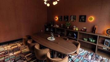 A conference room with a wooden table, six chairs, a chandelier, and a patterned floor.