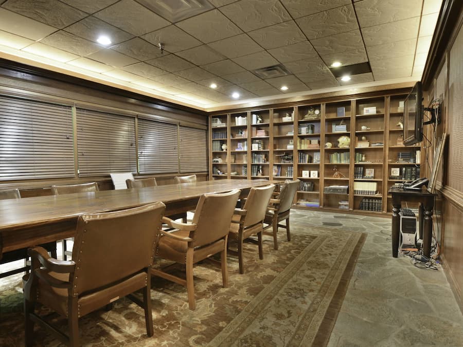 A conference room with a long table and chairs, surrounded by bookshelves filled with books and decorative items.
