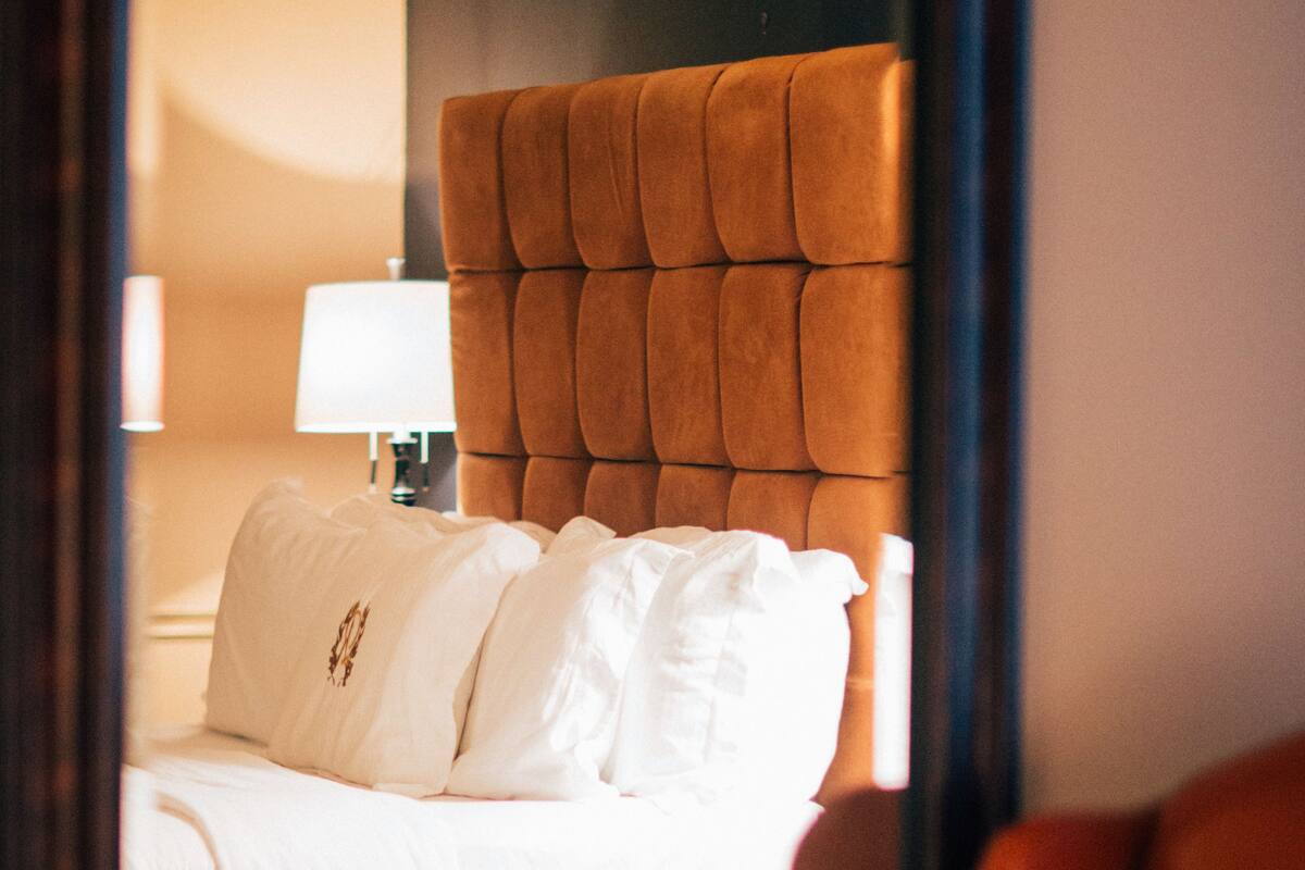 Een hotelkamer met een groot bed, een hoofdbord, een nachtkastje en een lamp.