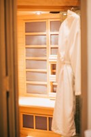 Uma sauna de madeira com bancos e um roupão branco pendurado na parede.