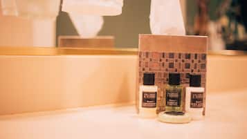 Una encimera de baño con artículos de aseo, incluyendo loción corporal y champú Gilchrist & Soames.