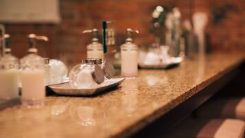 Een bar met zeepdispensers en een glas op een granieten aanrecht.