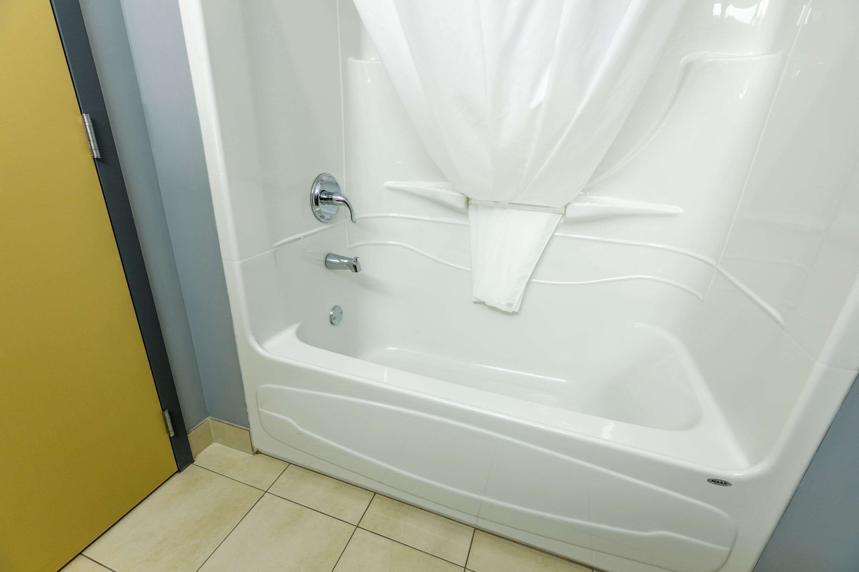 Een moderne badkamer met een witte badkuip, een douchegordijn en een handdoekhouder.