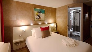 A hotel room with a large bed, a painting on the wall, a shower area, and a red curtain. - Best Western l'Atelier 117 (Maubeuge)