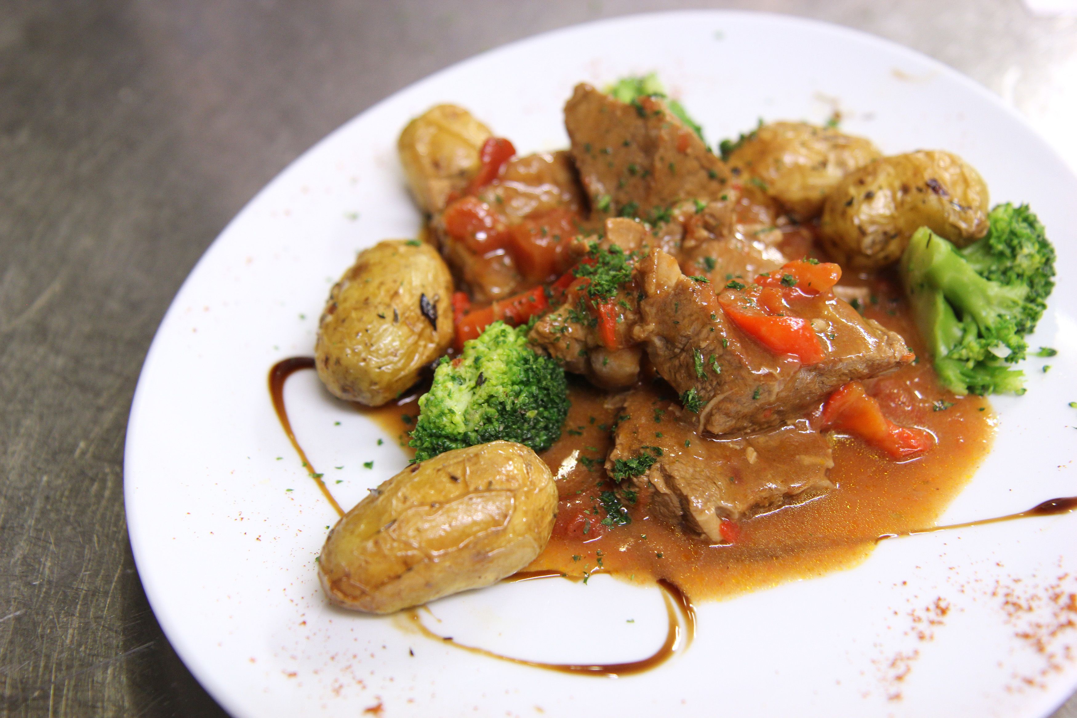 A plate of beef stew with vegetables and sauce.