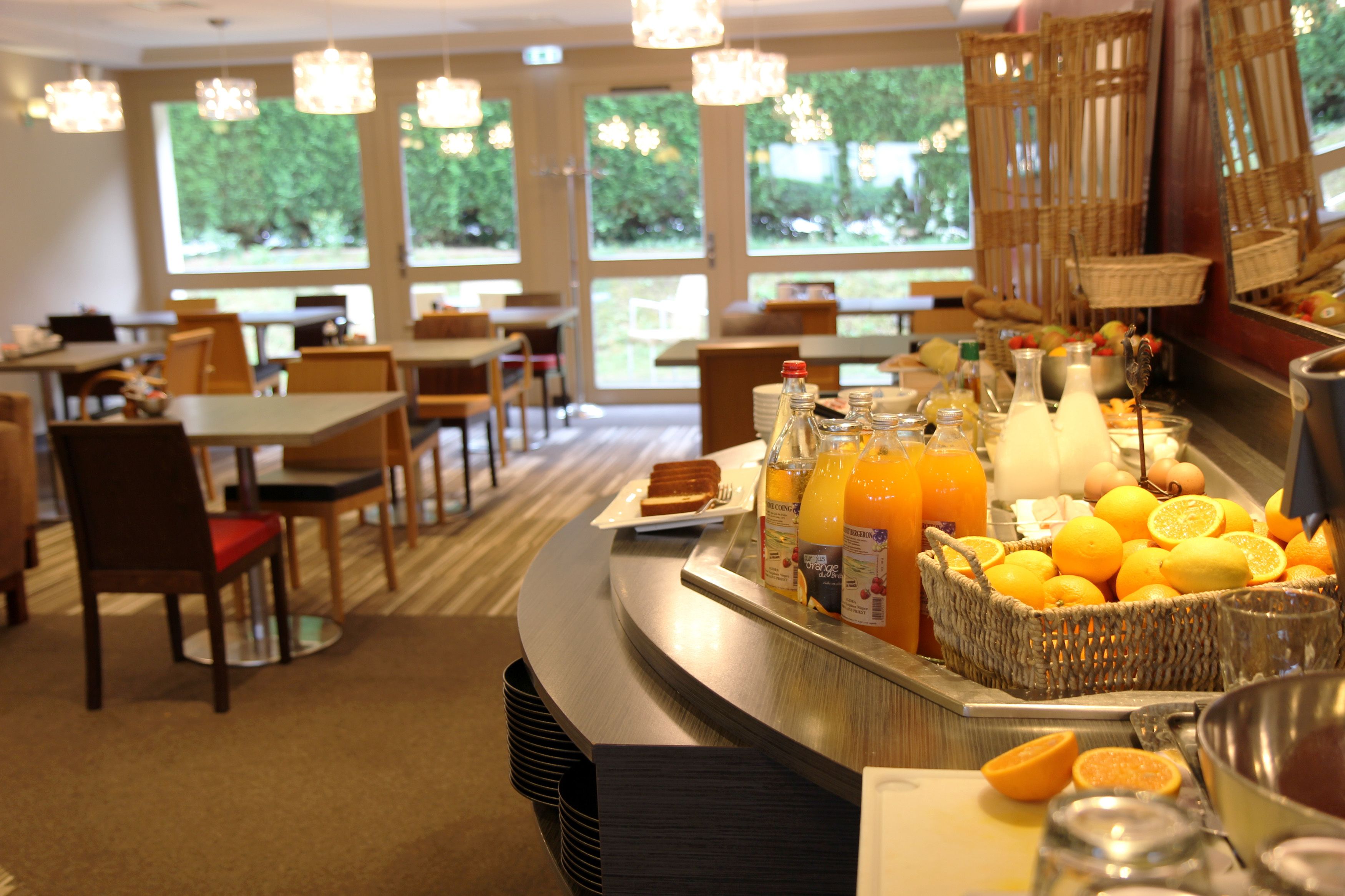 Een ontbijtbuffet met tafels, stoelen en diverse ontbijtartikelen, zoals fruit en sap.