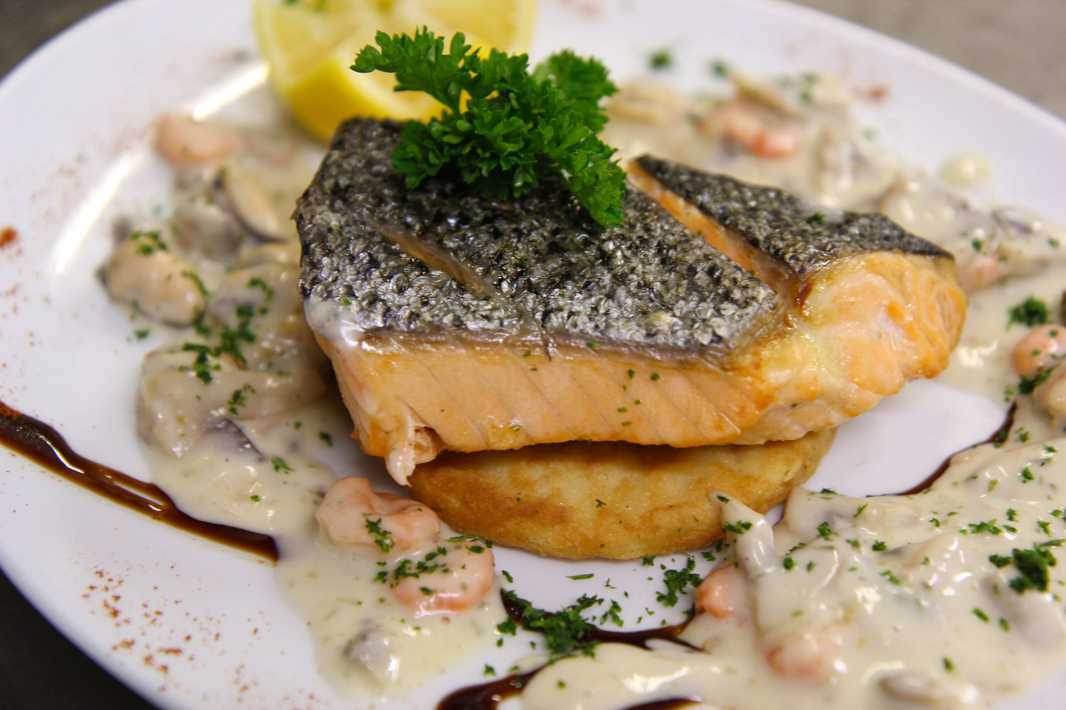A plate of salmon with a creamy sauce, garnished with parsley.