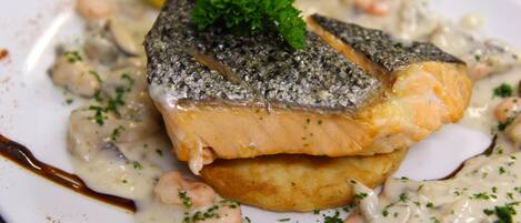 A plate of salmon with a creamy sauce, garnished with parsley.