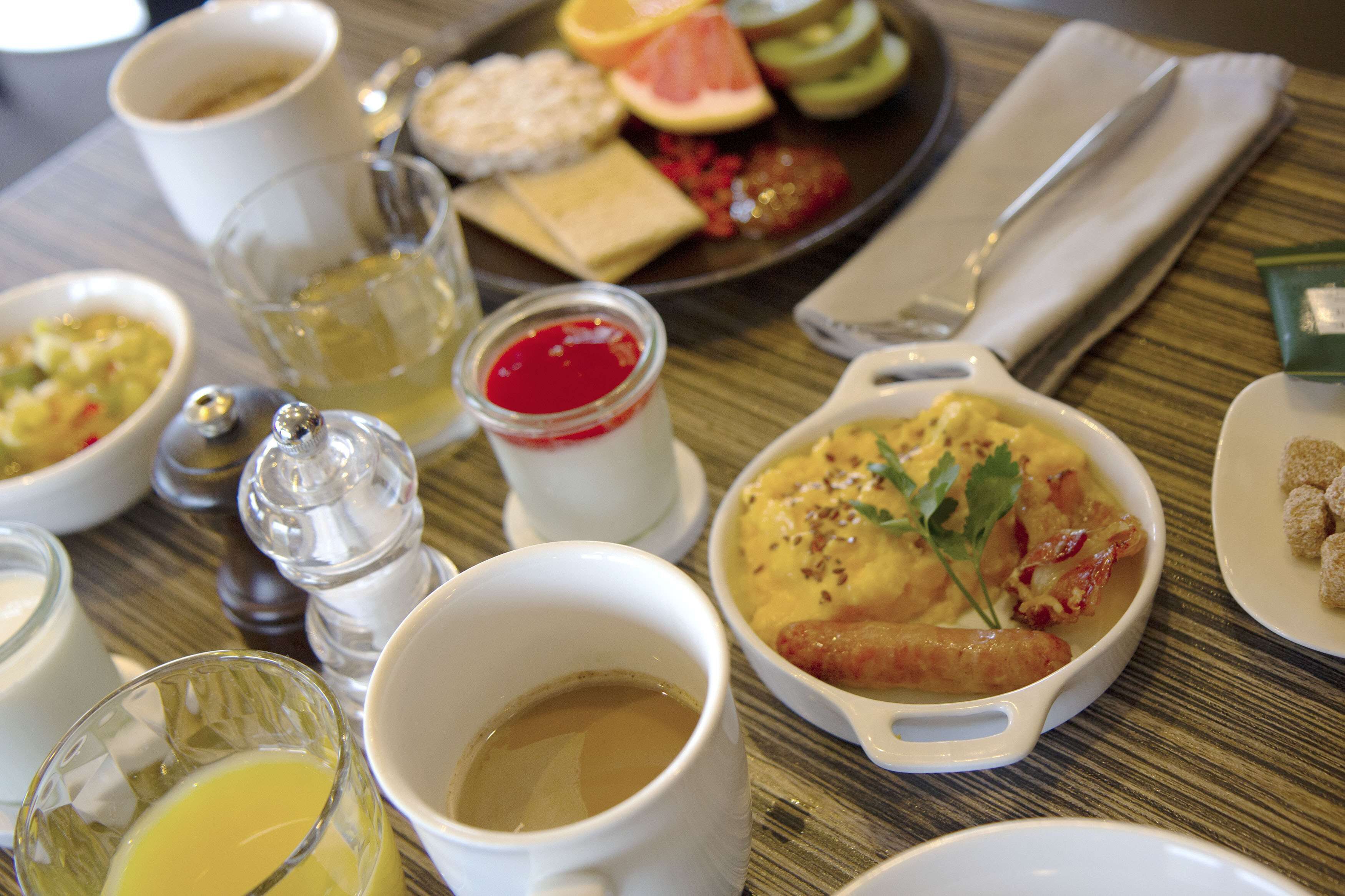 Una mesa de comedor con varios platos, entre ellos un tazón de sopa, un plato de fruta cortada y una taza de café.
