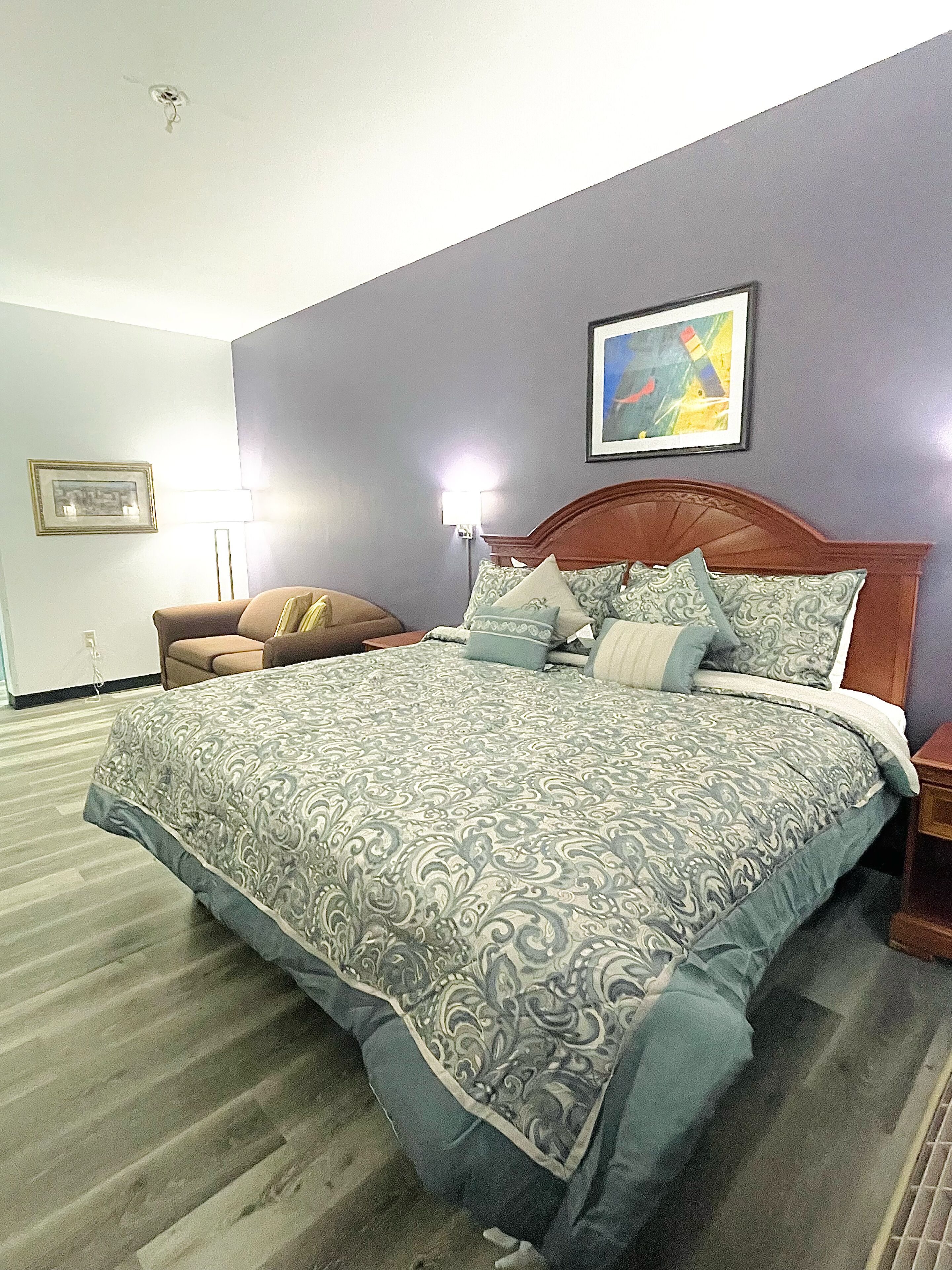 Un dormitorio ordenado con una cama grande, una silla y una mesita de noche.