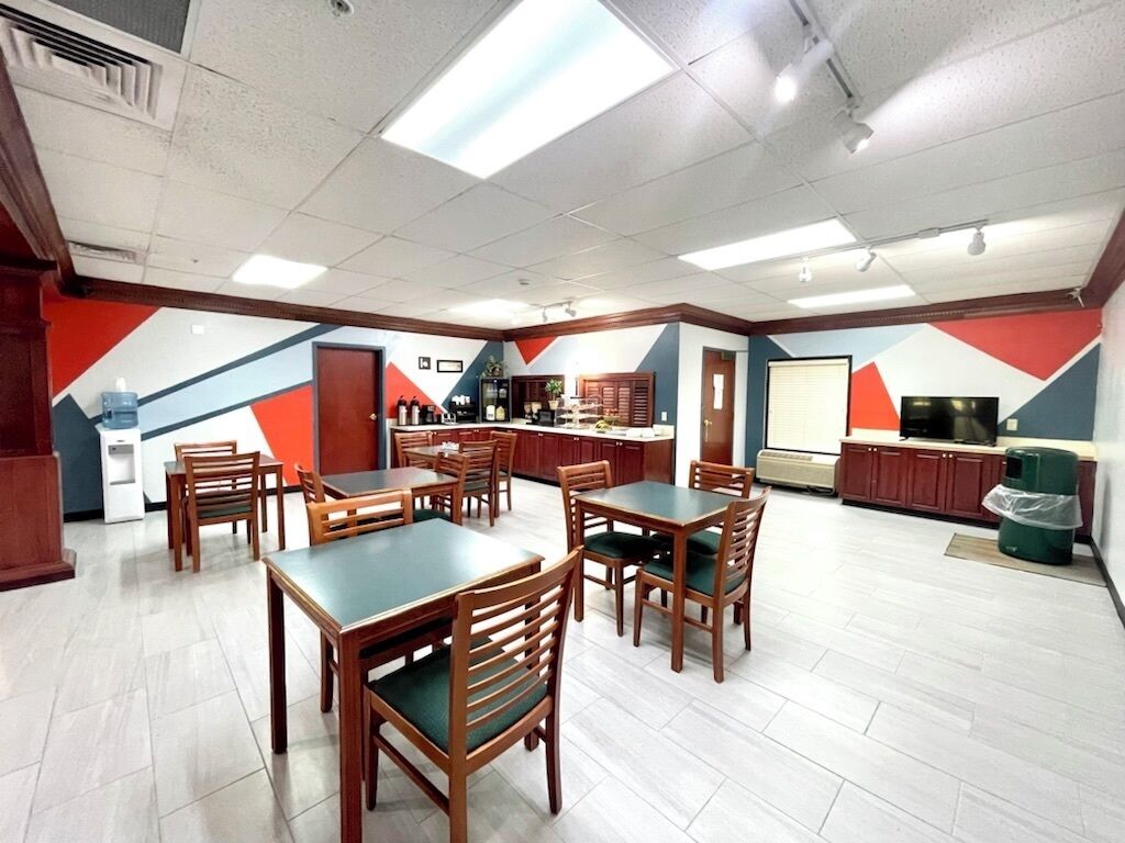 Un ristorante dall'arredamento moderno, con tavoli e sedie in legno, un bancone e una zona cucina.