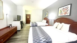 A hotel room with two beds, a desk, a television, and artwork on the walls.