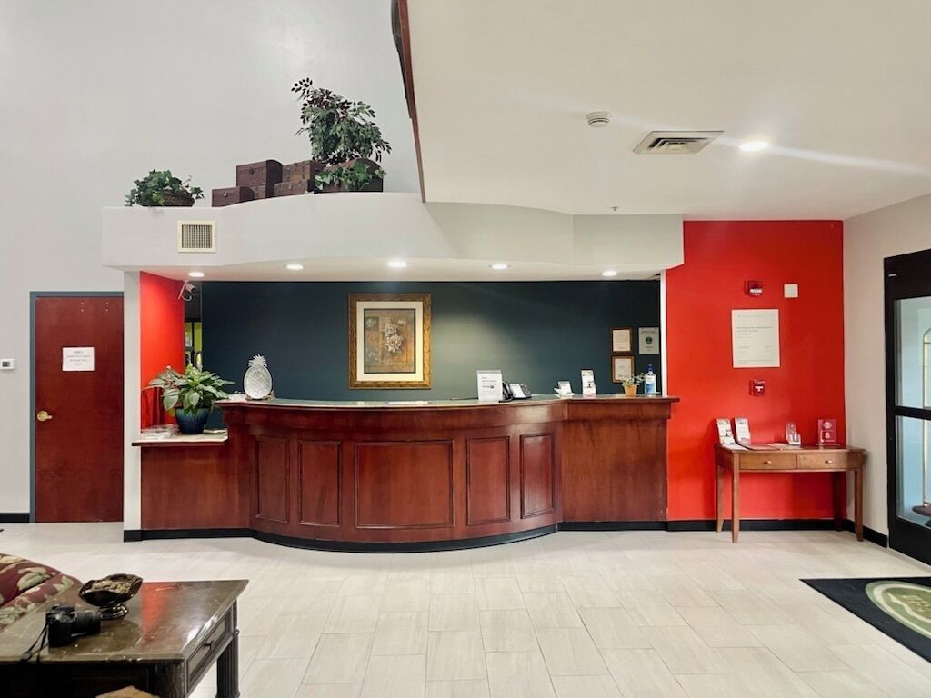 A reception area with a wooden reception desk, a framed picture above it, and a red accent wall.