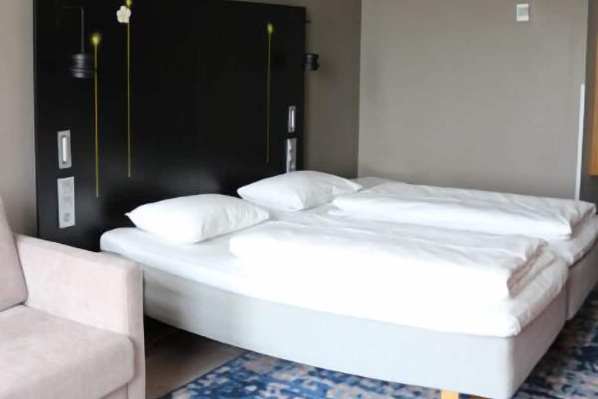 Una camera d'albergo moderna con un letto grande, un divano e un tavolino.