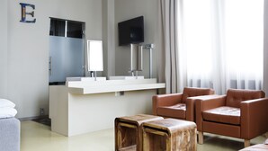 A modern hotel room with a white reception desk, a flat-screen TV, a large window with curtains, and two leather armchairs. - Comfort Hotel Grand Central (Oslo)