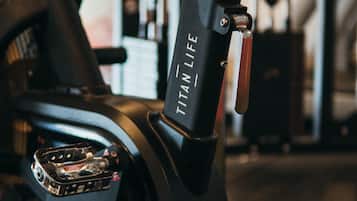 A stationary exercise bike with the brand name "Titan Life" visible on the handlebar.