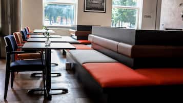 A modern restaurant with long communal tables and cushioned seating areas.
