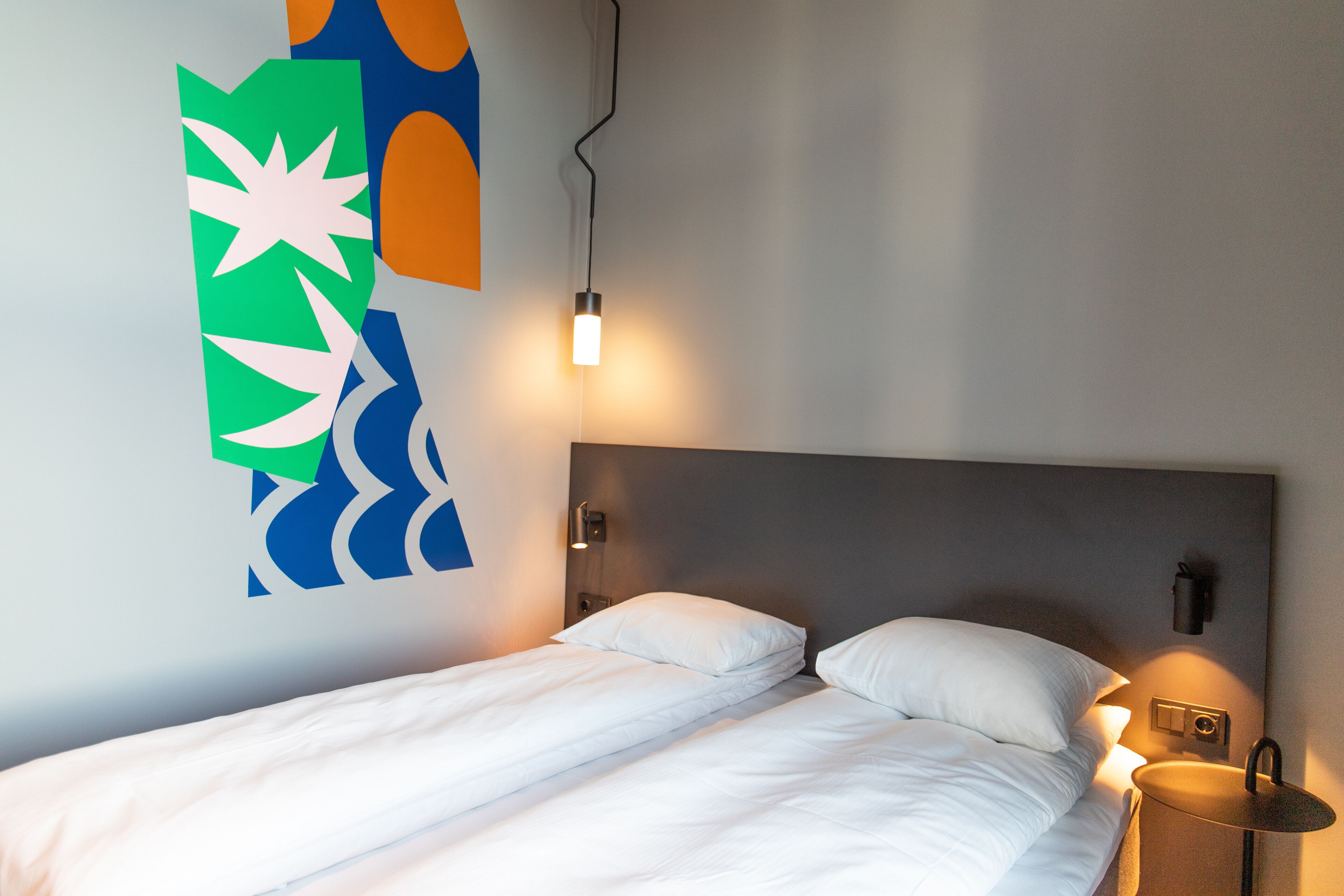 Una cama bien hecha con sábanas blancas en una habitación de hotel moderna.