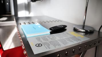 Ascensor metálico con un cuaderno azul, un control remoto negro y un letrero blanco con texto.