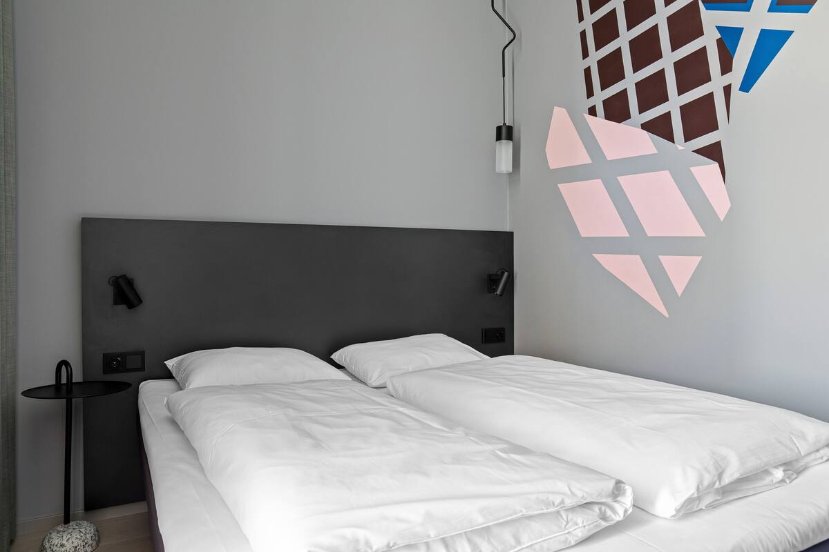 Una camera da letto moderna con un letto grande, un comodino e una lampada a parete.