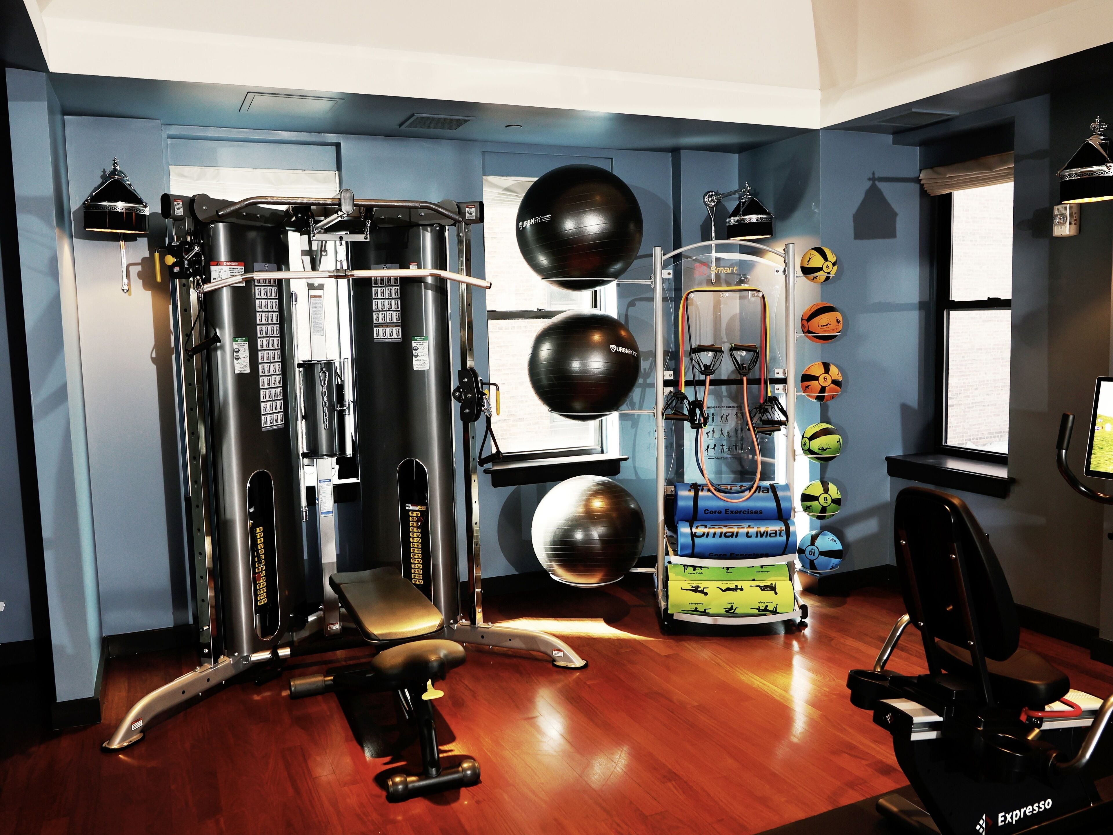 Une salle de sport équipée de divers appareils d’exercice, notamment une machine à câbles, un banc de développé couché et un vélo d’appartement.