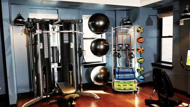 A gym with various exercise equipment, including a cable machine, a bench press, and a stationary bike. - The Ned NoMad (New York)