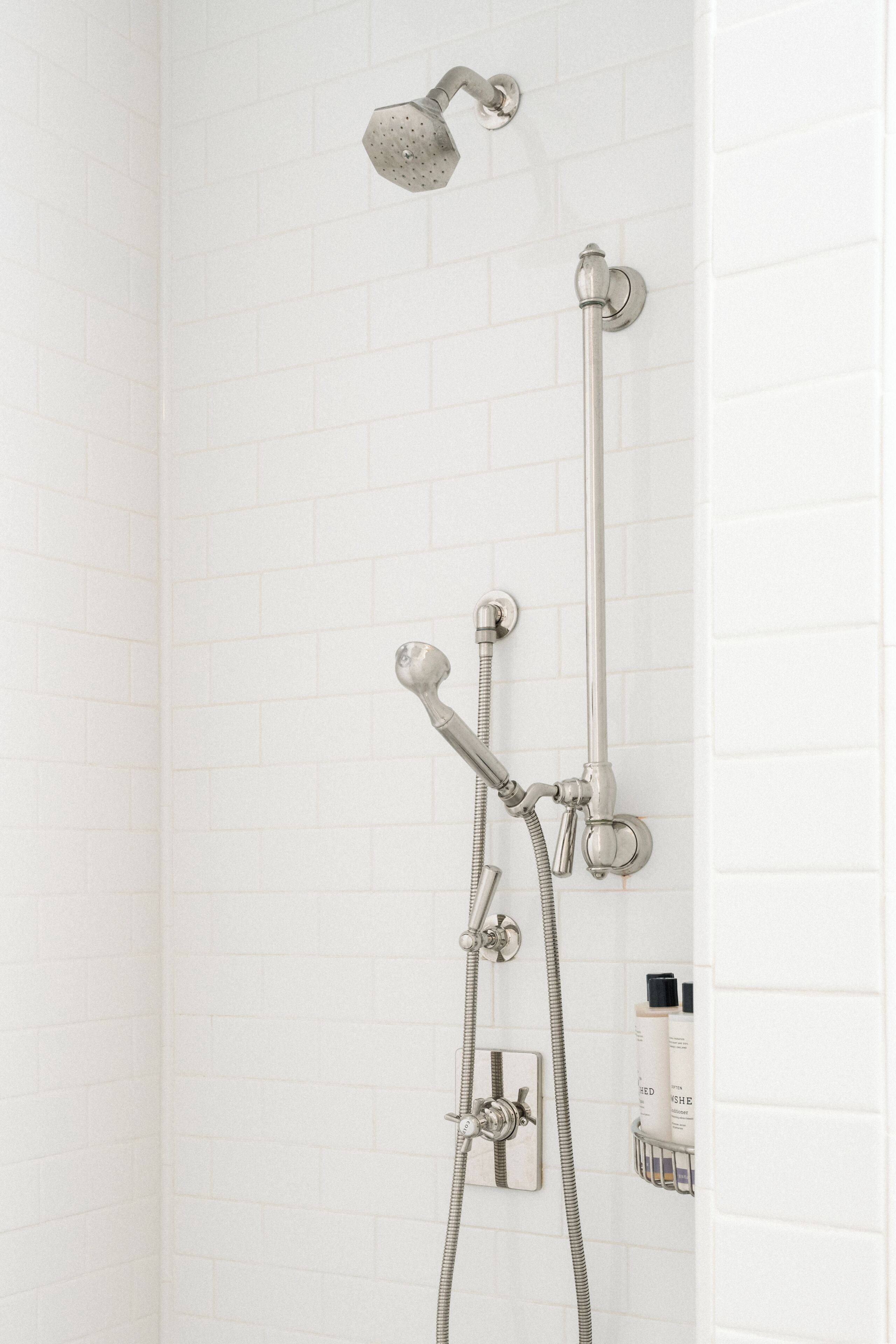 Une douche équipée d’un pommeau de douche à main, d’un pommeau de douche fixe et d’un accessoire de douche à main.